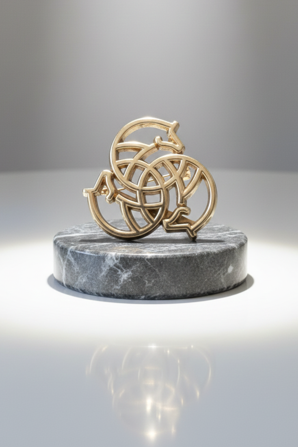 Gold decorative item on a gray marble base against a gray background