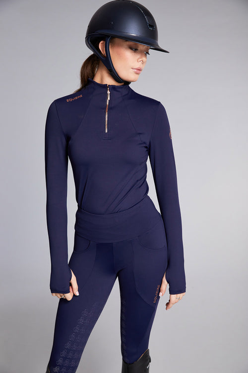 Person wearing a navy blue equestrian outfit with a helmet on a gray background